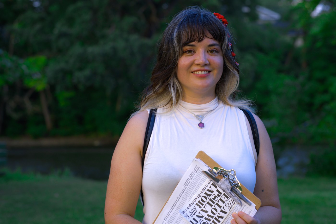 Amber Fellows outdoors holding campaign materials in a neighborhood setting.