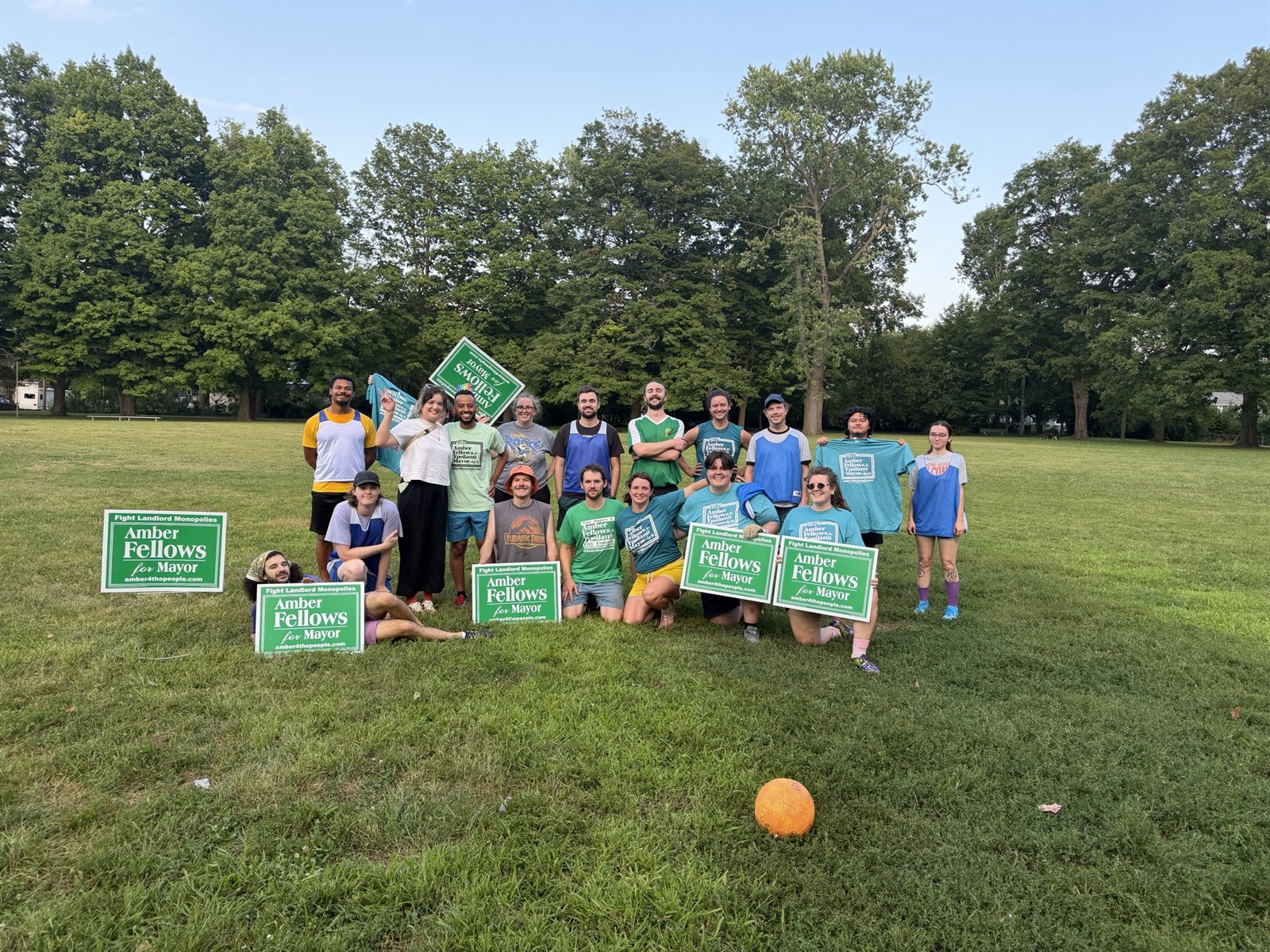Amber Fellows standing with campaign volunteers holding signs and shirts in a Ypsilanti park.