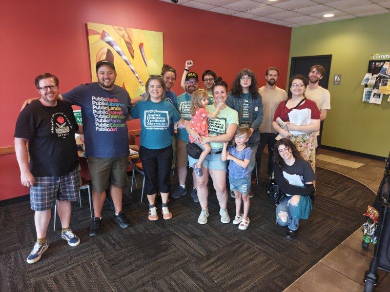 Amber Fellows standing with a large group of supporters and community members indoors.