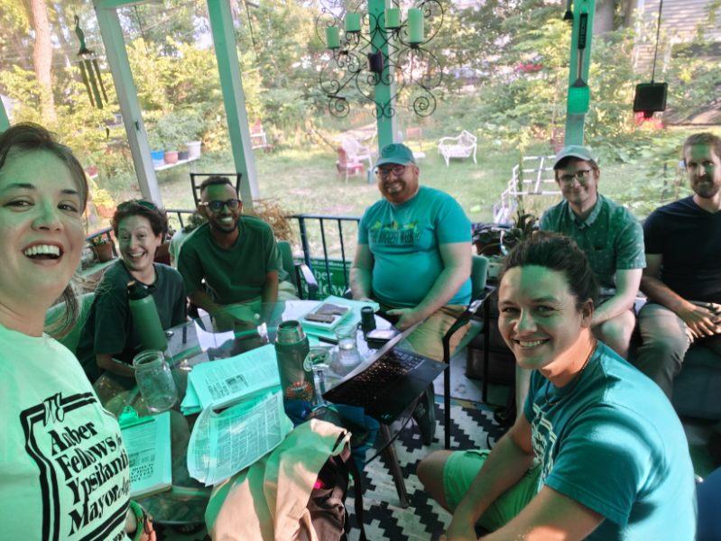Amber Fellows and campaign volunteers meeting together around a table on a porch.